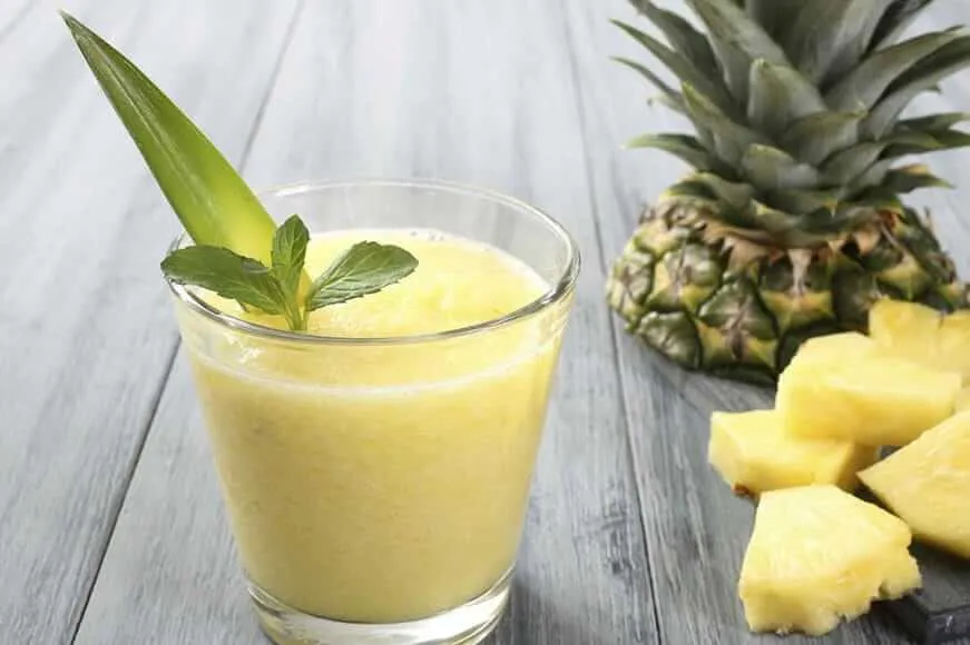 Szklanka soku z ananasa i limonki obok kawałków ananasa